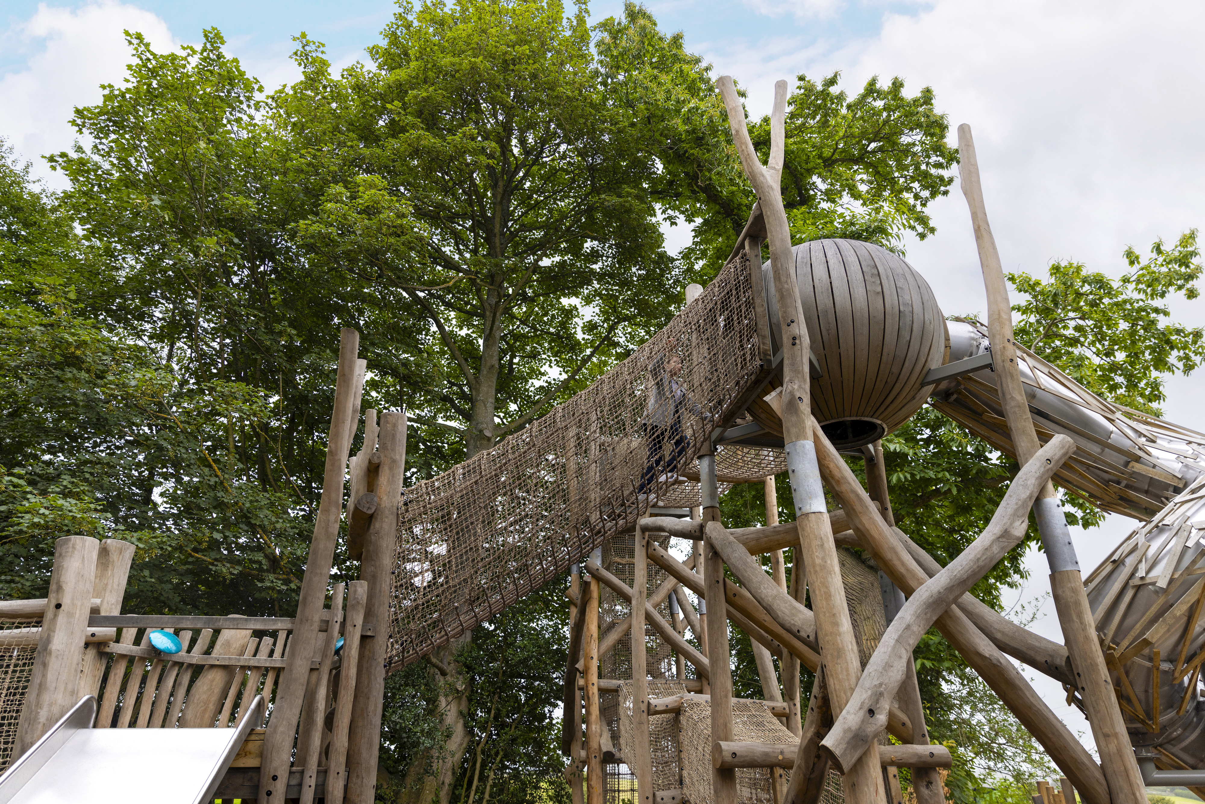 The play area at Belsay featuring lots of wooden play equipment and walkways in a woodland setting.