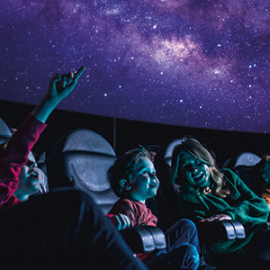 Family inside a planetarium in blue darkness.